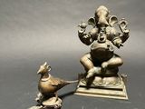 brass statue of ganji with a bird on a stand
