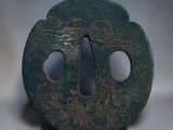 a small green metal object with a hole in it