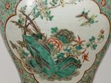 a green vase with a bird and flowers on it