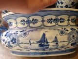 a person holding a blue and white vase with a sailboat on it