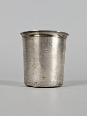 a silver cup with a handle on a white surface