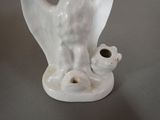 a white vase with a bird on it on a table