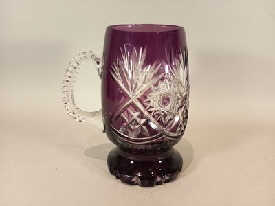 un verre violet avec une anse, posé sur une table