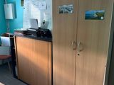a room with a desk, cabinets, and a chair in it