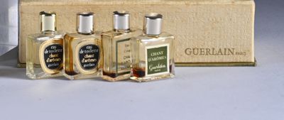 three small bottles of perfume sitting in front of a box