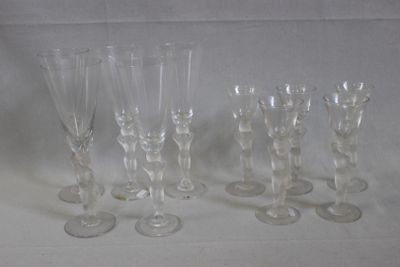 six verres à vin transparents sont alignés sur une surface blanche