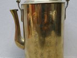 a brass tea pot with a handle on a white surface