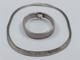 a close up of a silver necklace and bracelet on a white surface