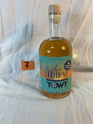 a bottle of rum sitting on a bed with a tag