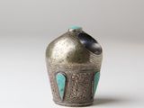an old silver vase with a turquoise stone in the top