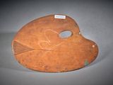 an old wooden mask with a tag on it sitting on a table
