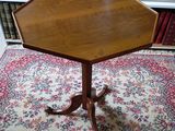 an octagonal table with a wooden top on a rug in front of a bookshelf