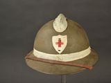 a helmet with a red cross on it on a stand