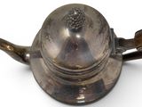 a silver teapot with a handle on a white surface