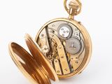a close up of a pocket watch on a white surface
