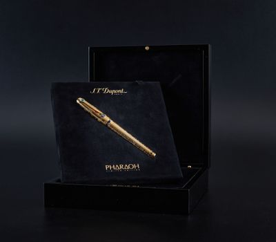 un stylo doré dans une boîte noire sur fond noir