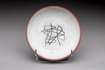 a white plate with a brown rim with a design on it