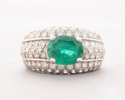 a close up of a ring with a green stone surrounded by white diamonds