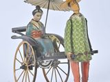 figurine of a woman in a green dress and a man in a green coat with an umbrella in a carriage