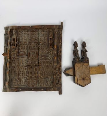 une photo d'une porte en bois ornée de sculptures, adossée à un mur