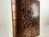 an old book with a brown cover sitting on top of a table