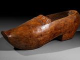 an old wooden shoe is sitting on a black surface