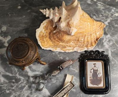 une photo d'une photo représentant une femme assise sur un coquillage, avec un décapsuleur et un porte-clés
