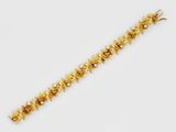 a gold bracelet with flowers and pearls on a white background