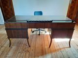 a desk with a glass top and a chair in a room