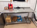 une cuisine équipée d'une table en acier inoxydable sur laquelle est posé une planche à découper