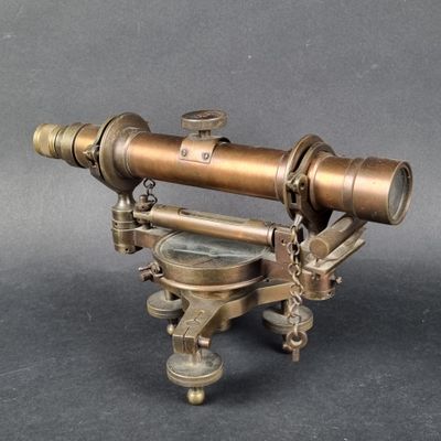 an old brass telescope on a stand on a gray background