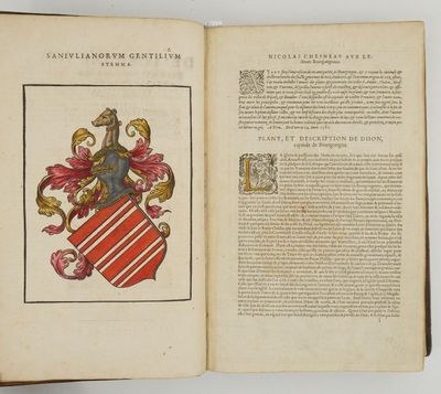 un livre ouvert sur lequel figure l'image d'un blason et un blason