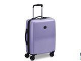 La valise violette repose sur ses roulettes, posée sur une surface blanche.