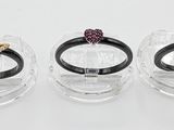 trois bagues sont posées dans un support transparent sur une surface blanche