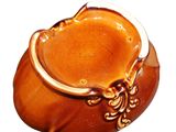 a brown vase with a gold handle on a white background