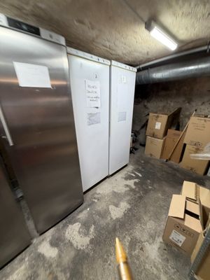 deux réfrigérateurs qui se trouvent dans une pièce où il y a des cartons par terre