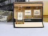 two bottles of chanel perfume sitting on a table next to a purse