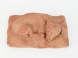 figurine of a dog sleeping on a blanket on a white surface