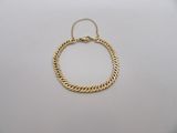 un bracelet en chaîne d'or muni d'un fermoir, posé sur un fond blanc