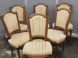 six chaises et une table dans une pièce aux murs gris