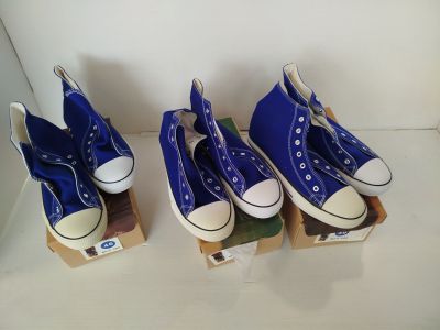 Trois paires de Converse bleues sont exposées dans une vitrine.