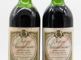 two bottles of red wine sitting next to each other on a white surface