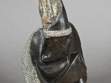 statue of a woman with a shawl on her head and a rock in the background