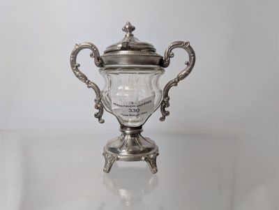 an antique silver plated trophy sitting on top of a glass table