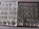 a lot of coins that are in a red binder