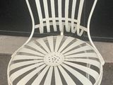 a white metal chair that is sitting in front of a black wall