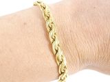 someone is wearing a gold bracelet with a braid design on it