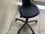 une chaise noire et un tuyau posés par terre devant une porte