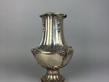 an antique silver vase on a white surface with a gray background