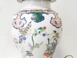 a white and blue vase with a gold base on a table